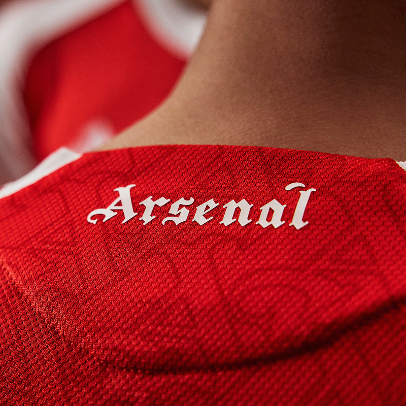 Arsenal authentic 3rd jersey fabric close-up with 'Arsenal' wordmark on red knit