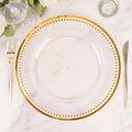 Clear charger plate with gold beaded rim on a marble tabletop.