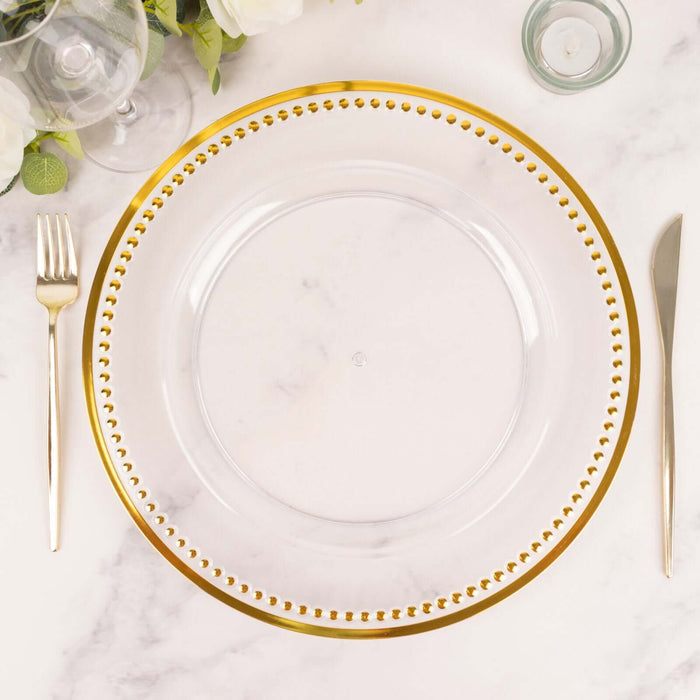 Clear charger plate with gold beaded rim on a marble tabletop.