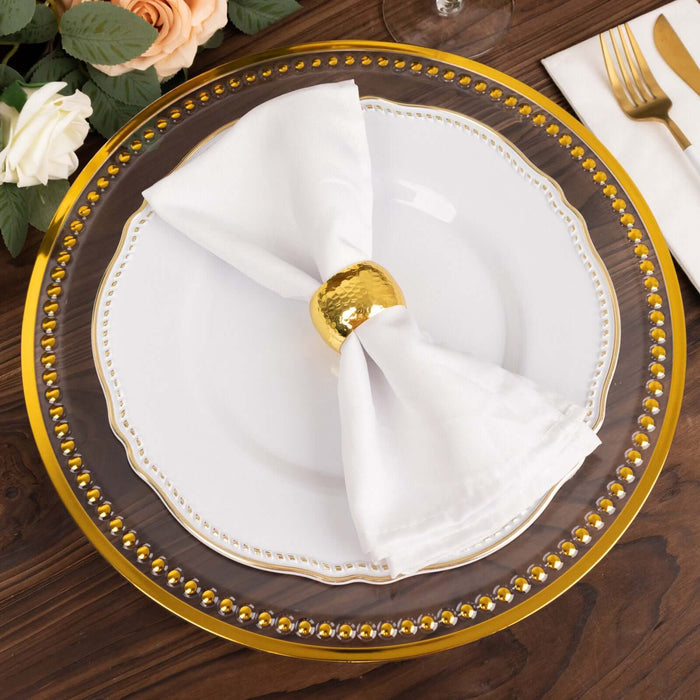 Elegant table setting with white plate, golden napkin ring, and decorative charger.