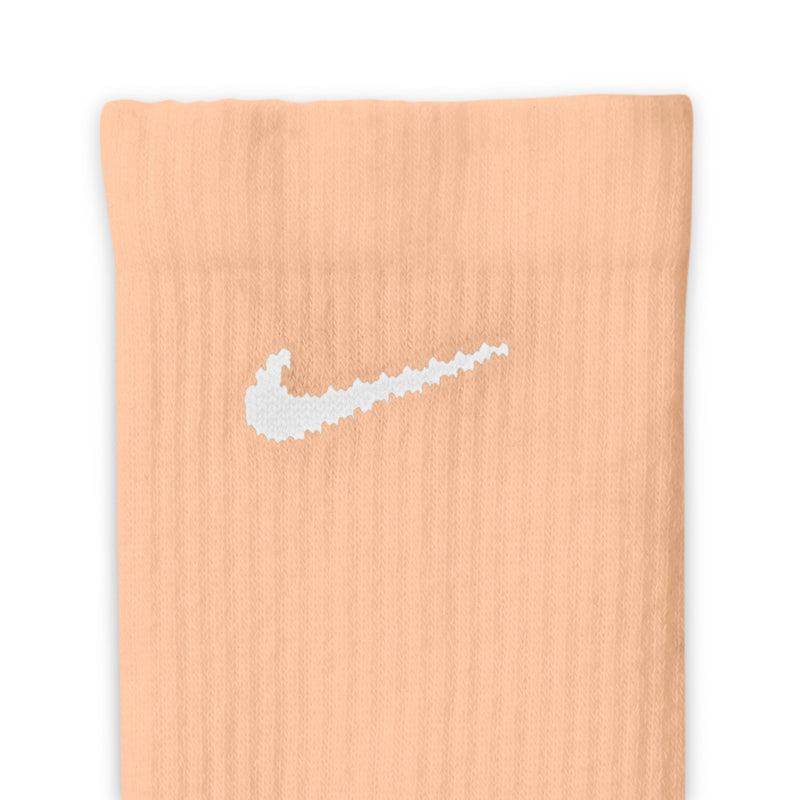 Crew sock close-up in pastel peach knit with Nike Swoosh logo centered