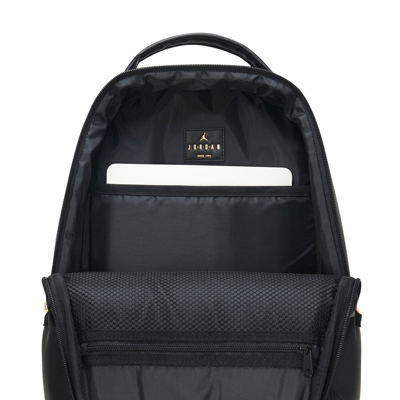 Black backpack interior with top handle, zip pocket, and white label patch