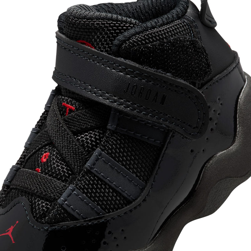 Close-up of black toddler sneaker upper with stitched straps, red Jumpman markings, and texture.