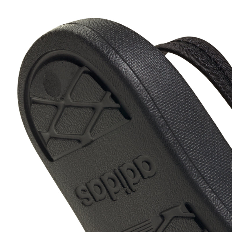 Close-up of black toddler slide outsole with adidas logo and textured tread pattern