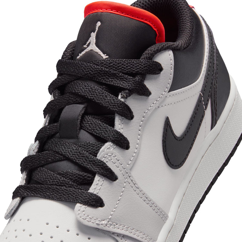Close-up youth sneakers: black laces, white panels, black Nike swoosh, red collar