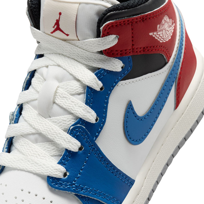Kids AJ 1 mid-top sneaker close-up with white laces, blue swoosh, and red-blue panels