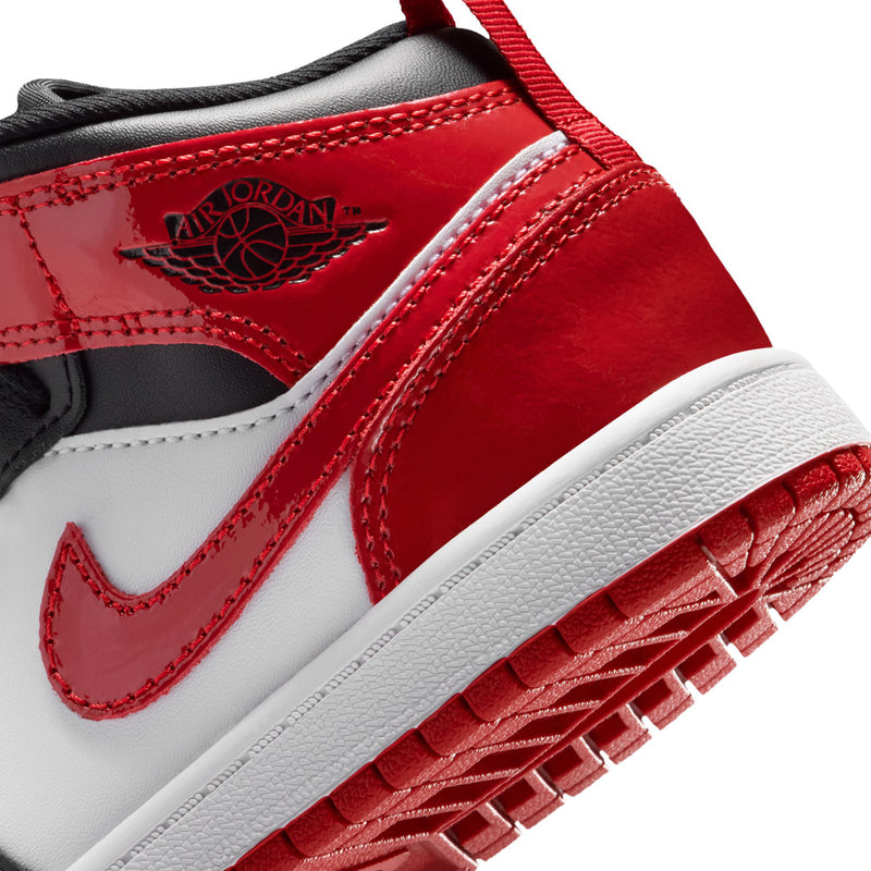 Close-up kids mid-top sneakers with red leather strap detail and white midsole.