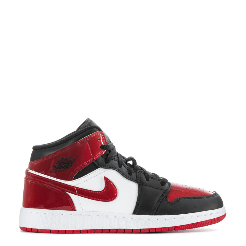 Youth mid-top sneakers in black, red, and white with swoosh and lace-up.