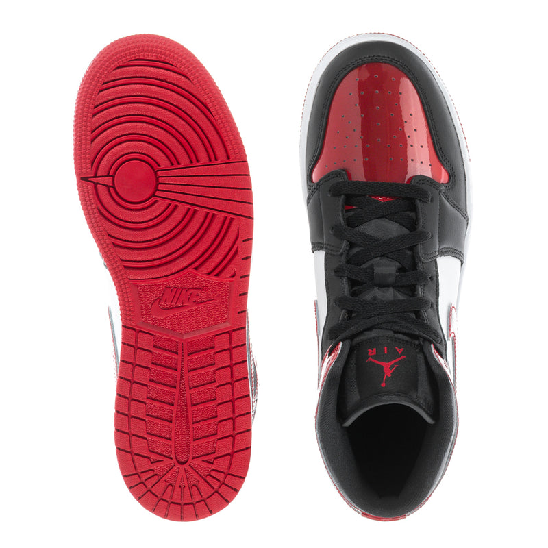 Youth mid-top sneakers showing red outsole and black laces on white sole.