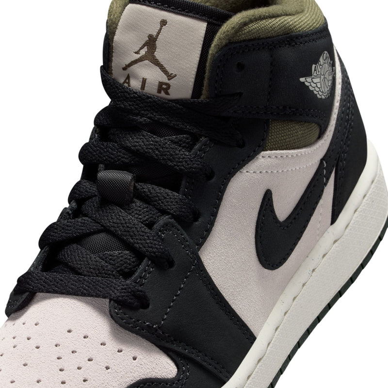 Youth mid-top sneaker upper close-up, black laces on off-white leather with Air tag
