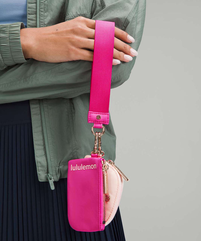 Side angle of the wristlet with an adjustable wrist strap in matching pink shade