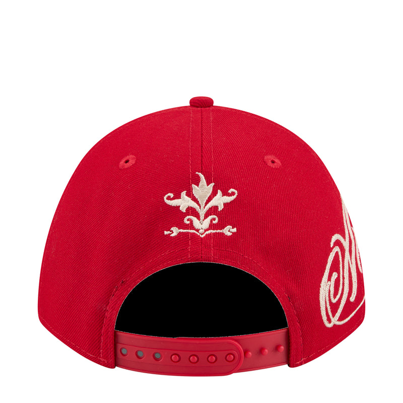 Red baseball cap back with white fleur-de-lis and scroll embroidery at crown.