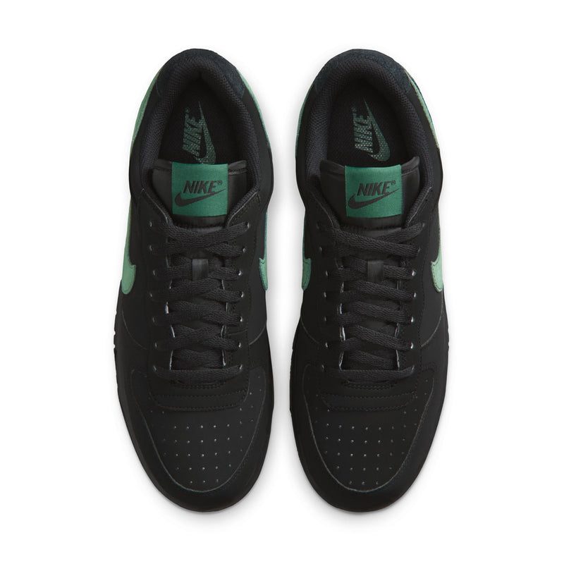 Black Nike sneakers with lace-up front and green NIKE tongue label.