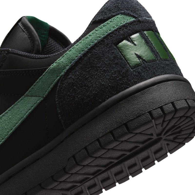 Black Nike sneaker with green trim and textured side panel detail.