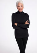 An older adult with short white hair is wearing the Woolx Brooke 1/4 Zip top and black pants, standing against a plain white background with arms crossed, smiling gently at the camera. | Kathy is 5'8", wearing a size S