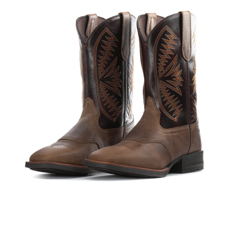 Tan cowboy boots with dark embroidered shafts, side pull straps, and black rubber sole