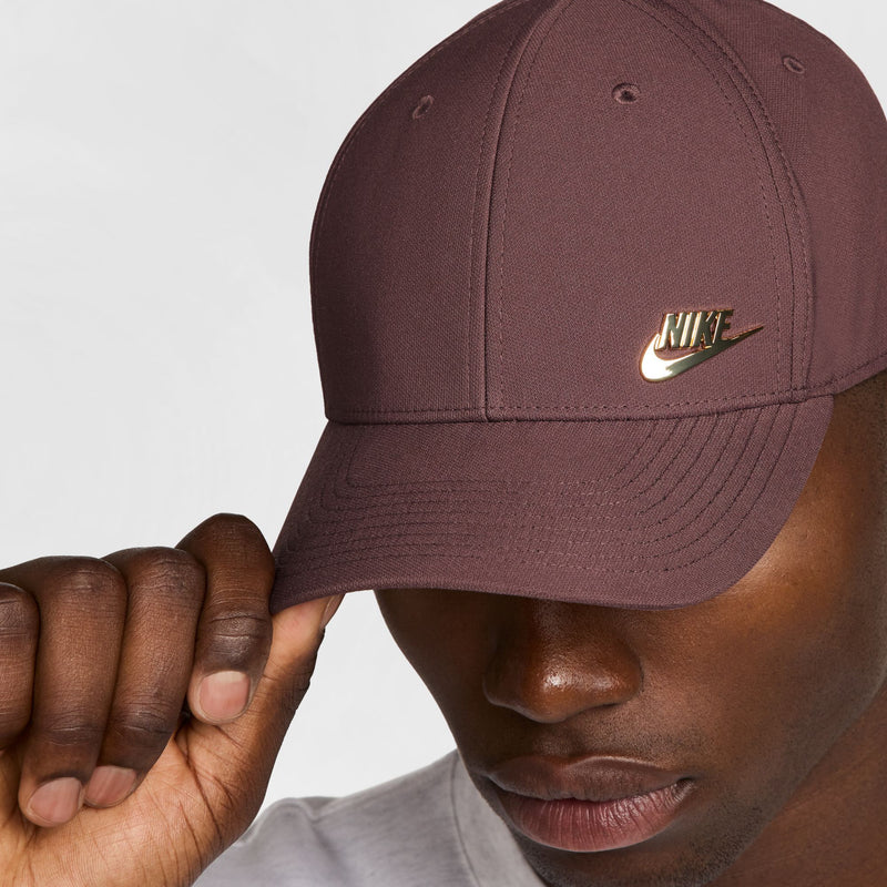 Nike club cap in mauve with gold swoosh logo; hand holds the brim