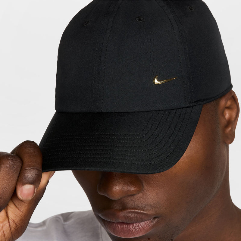 Black strapback cap side view with metallic gold Nike Swoosh and curved brim.