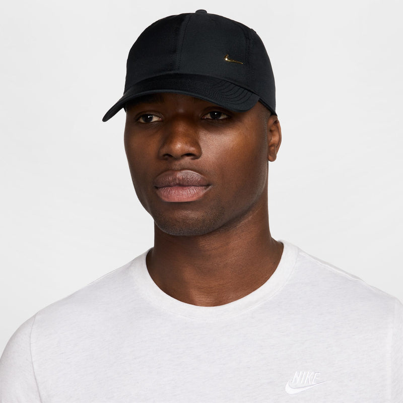 Black strapback cap with metallic gold Nike Swoosh, worn front view, low-profile crown.