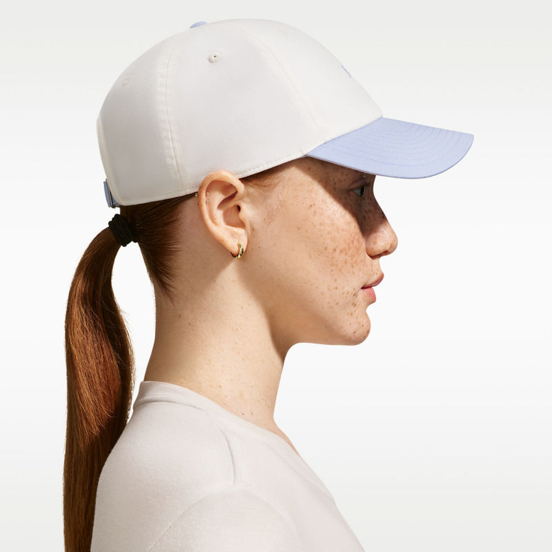 Cream cap with curved light-blue bill, side profile view