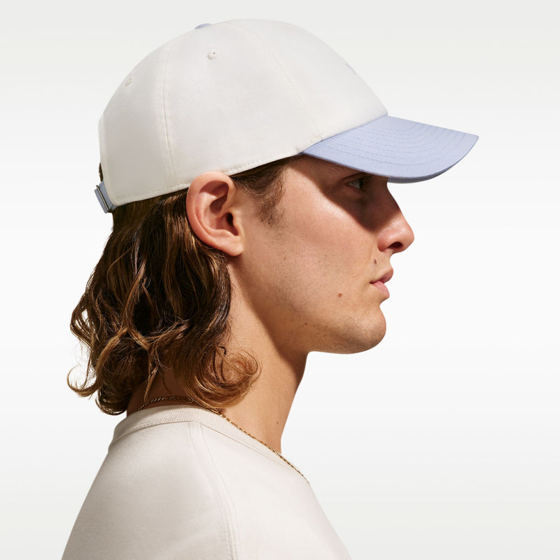 Cream cap with curved light-blue bill, angled side view