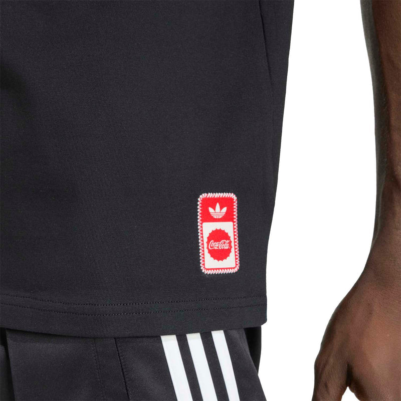 Black T-shirt hem with small red patch logo and trefoil mark