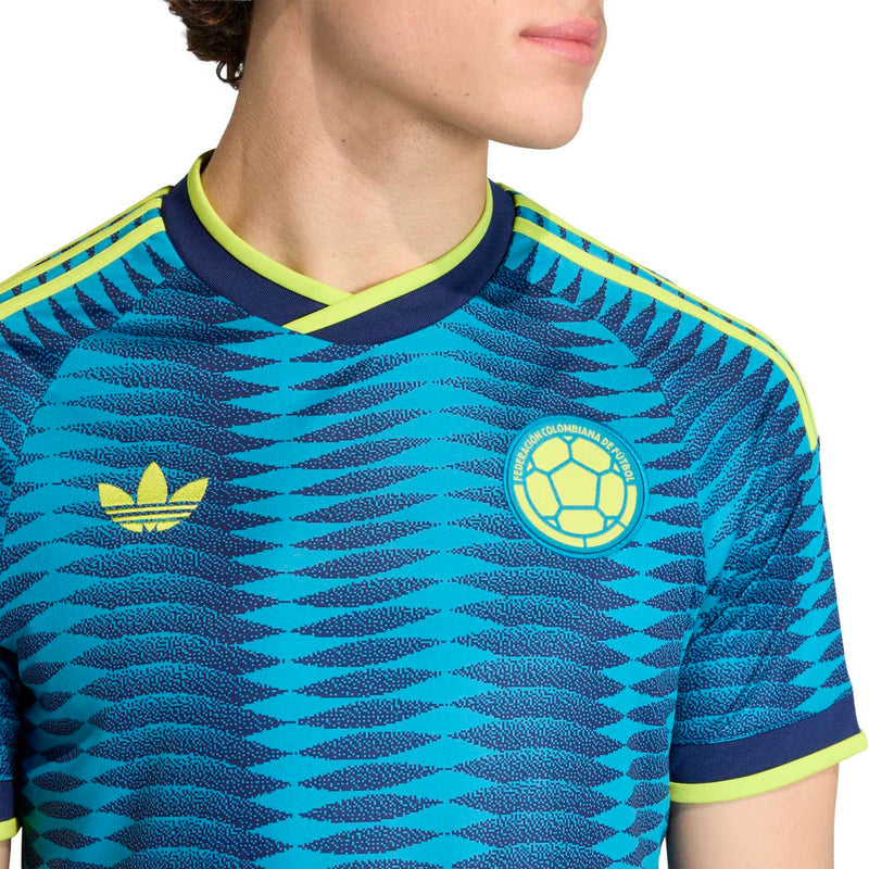 Men's Colombia away soccer jersey close-up: turquoise zigzag, yellow adidas logo and crest