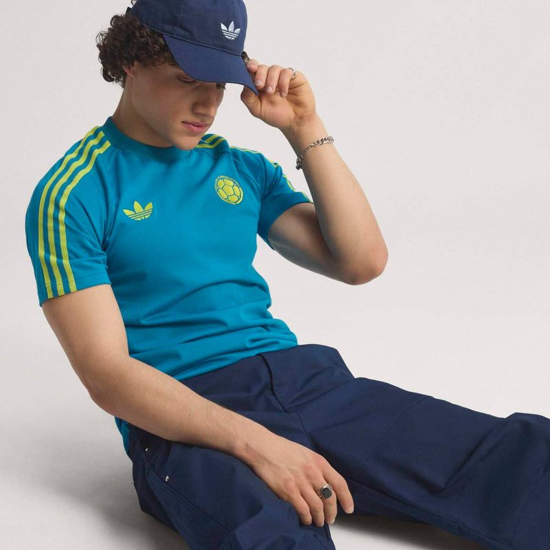 Teal soccer T-shirt with yellow sleeve stripes and crest emblem on upper chest