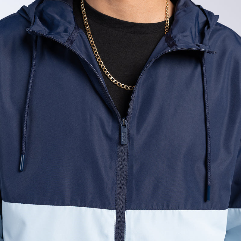 Navy and light-blue windbreaker hooded jacket with front zipper and drawstring.