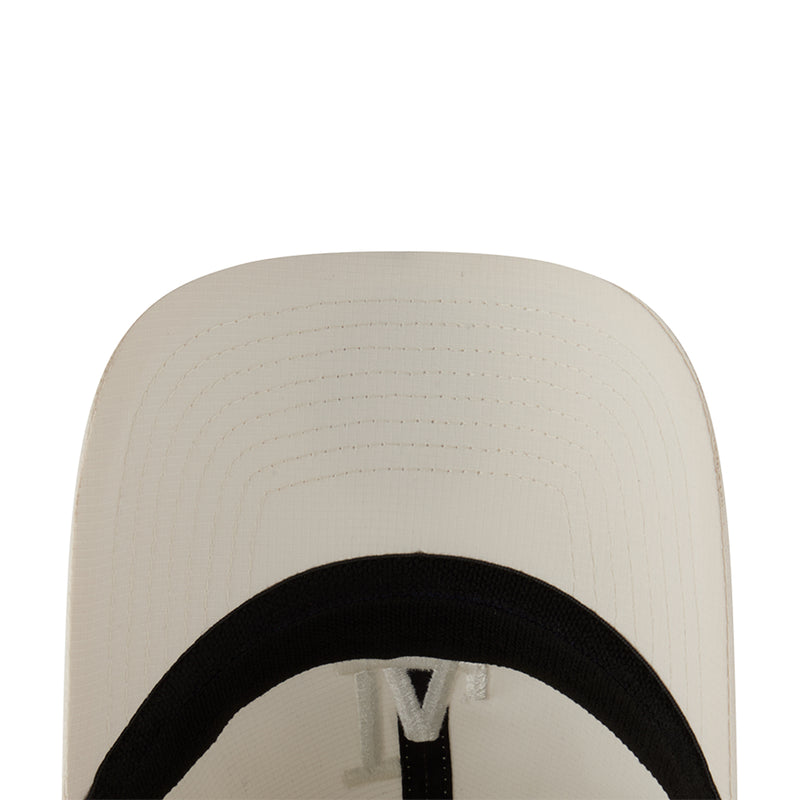 Cream cap interior close-up with black lining and adjustable strap hardware