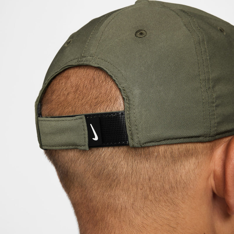 Nike cap close-up: black strap label with white swoosh on medium olive
