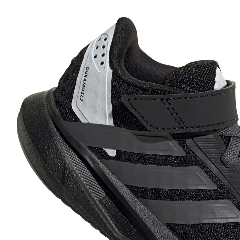 Kids black sneaker with white tongue label, hook-and-loop strap, and side stripe details