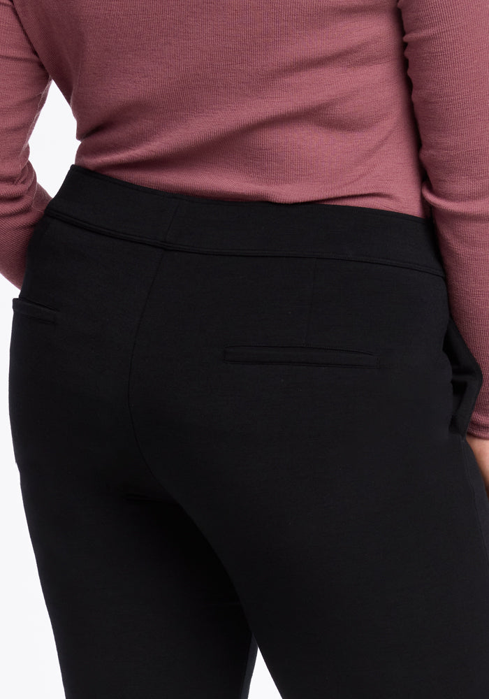 A person is shown from the back wearing a long-sleeved mauve sweater paired with the sleek Woolx Emerson Straight Leg Pants in black. The pants, made from smooth Merino Wool, feature two back pockets, with the image highlighting the waistband and upper section of the pants.