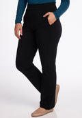 A person is wearing Woolx's Emerson Straight Leg Pants in black, paired with a long-sleeve teal top, their right hand casually resting in a pocket. With beige shoes completing the look, they exude comfort against the plain white background.