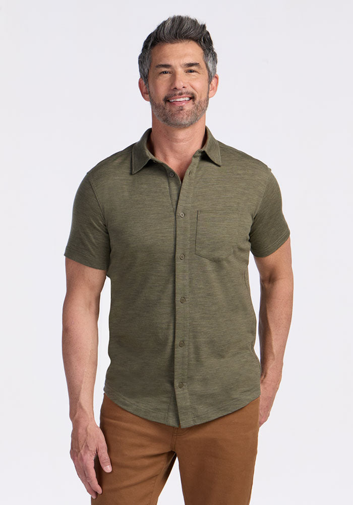 A smiling man with short gray hair and a beard wears the Woolx Endi Full Button Down Shirt in Sage Olive Melange and brown pants, standing against a plain white background. | Matthew is 6’, wearing a size L