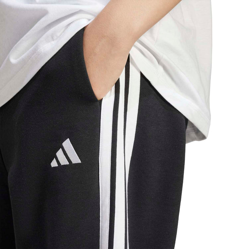 Women’s black track pants close-up: white 3-stripe detail and adidas emblem.