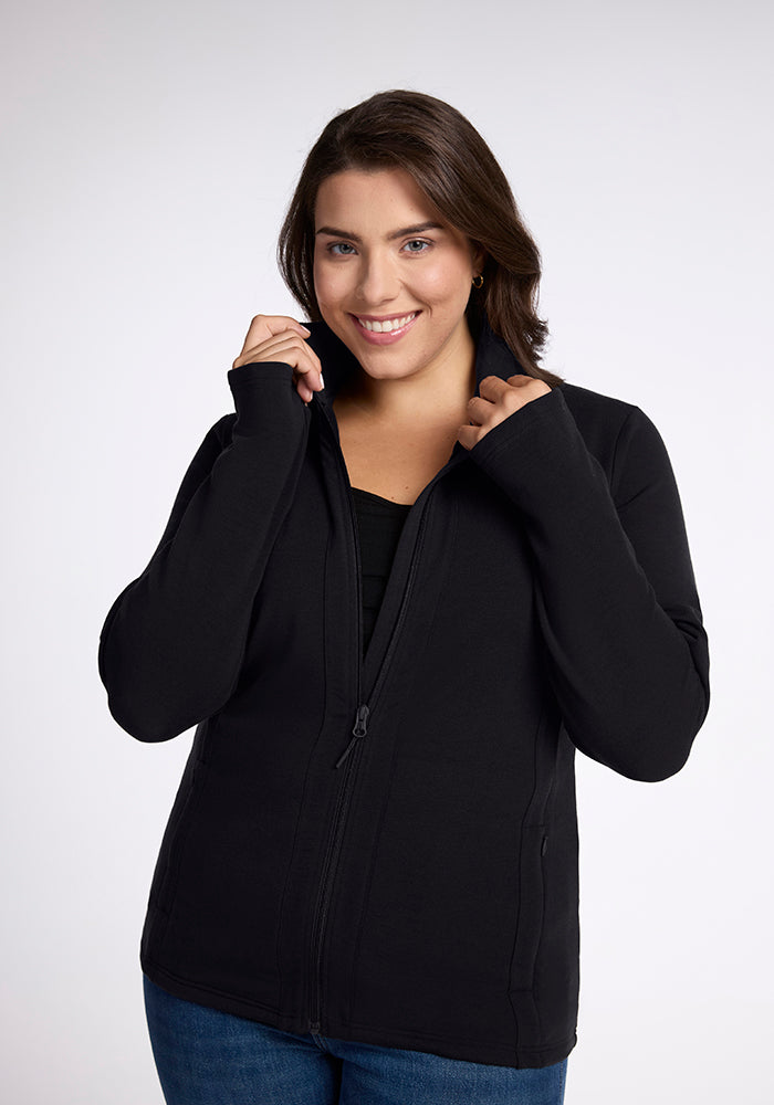 A smiling person with shoulder-length hair is wearing a flattering Finley Zip Up Sweatshirt in black from Woolx, made from Australian merino wool. They are holding onto the collar with both hands, against a plain white background. | Juliana is 5'10", wearing a size XL