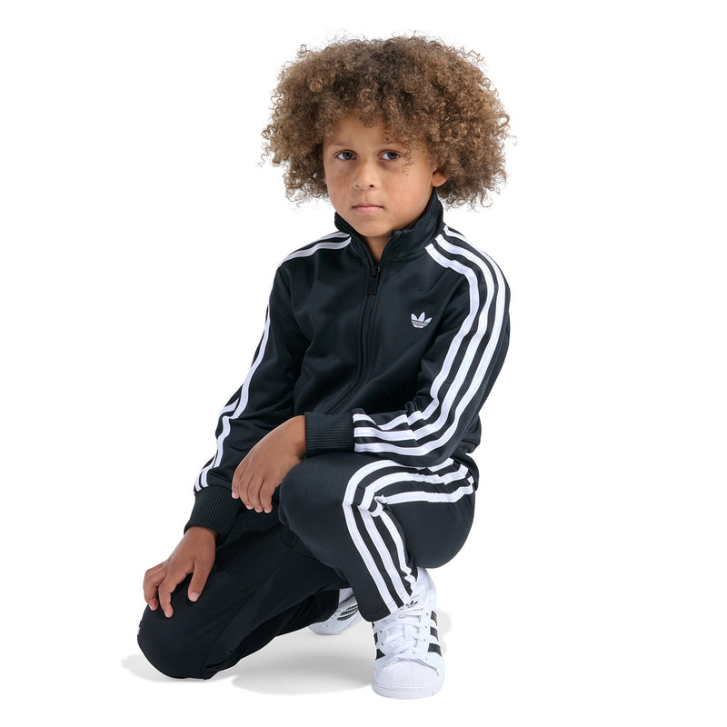 Kids black track set on kneeling model: zip jacket and striped track pants.