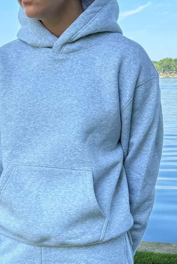 Close-up of gray fleece hoodie fabric and pocket outdoors by water