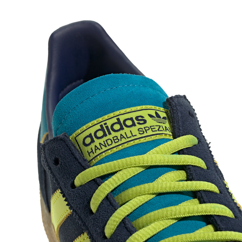 Close-up of men's sneaker toe and laces: navy suede with neon green stripes