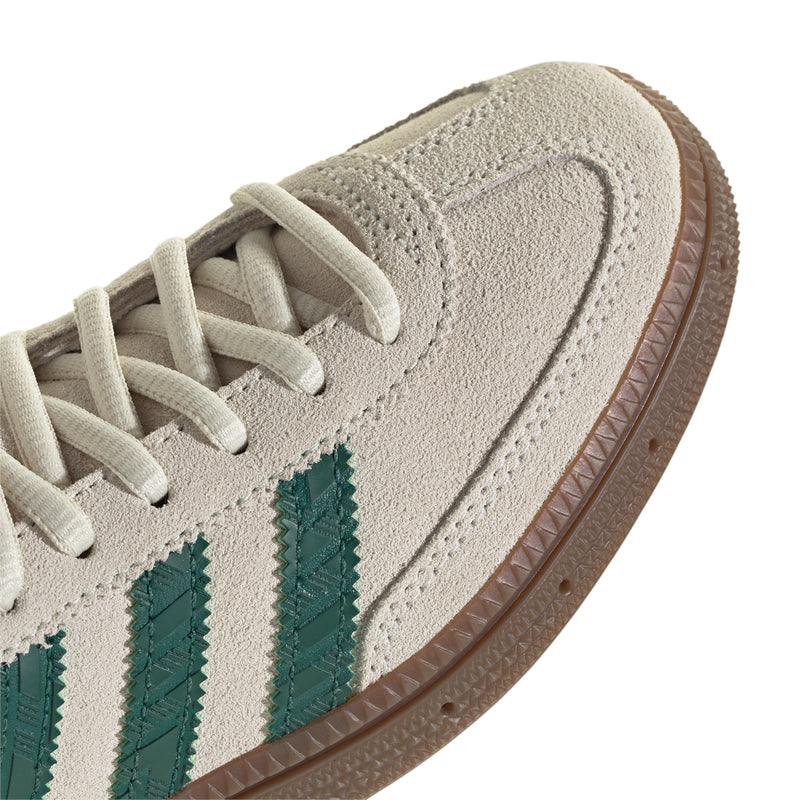 Youth sneaker upper close-up, off-white suede texture with green triple stripes