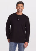 A man with short, dark graying hair and a beard is wearing the Jackson Henley - Black by Woolx, made of Merino wool, along with blue jeans. He is smiling and standing against a plain white background. | Matthew is 6', wearing a size L