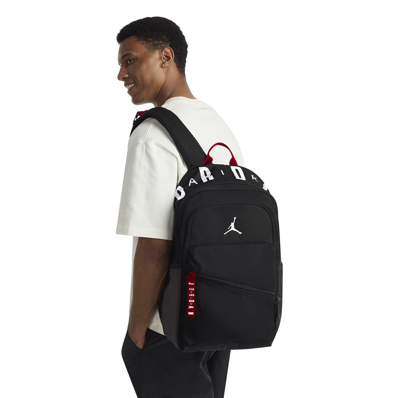 Black backpack worn on model's back with red handle accents and Jumpman logo
