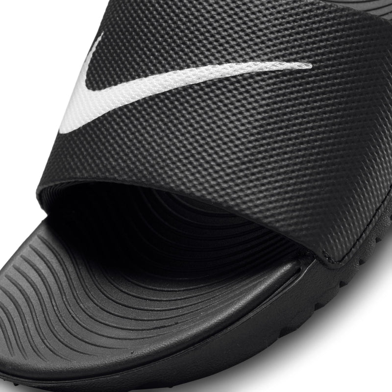 Youth black slide sandal strap close-up with white Nike swoosh and textured grip