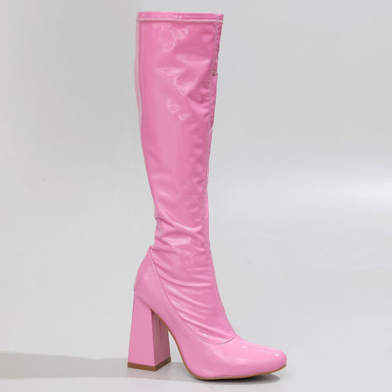 The La Gogo Calf Boot - Pink Wet Look - Street Sole, crafted from stretch vegan patent, is highlighted with its glossy pink finish and striking high block heel against a plain backdrop.