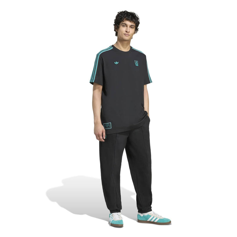 Men’s black Liverpool icon T-shirt with teal shoulder stripes, worn with black pants