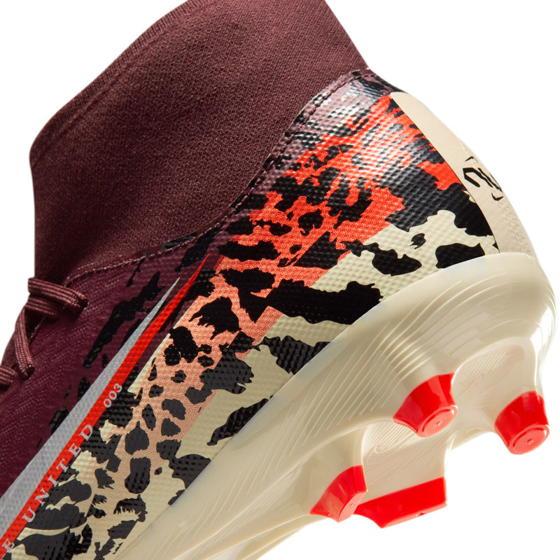 Close-up of burgundy soccer cleat outsole with red studs and leopard side