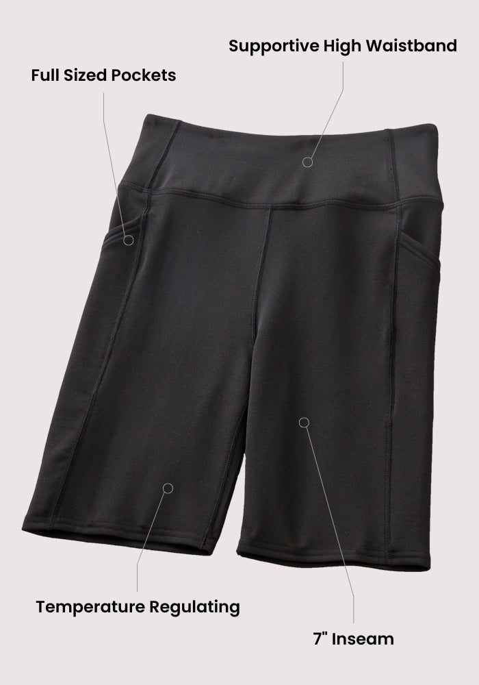 Woolx Merino Flex® Dani Bike Shorts in Black laid flat on a light background, with labels highlighting moisture-wicking Merino wool fabric, supportive high waistband, full-sized pockets, and a 7-inch inseam.