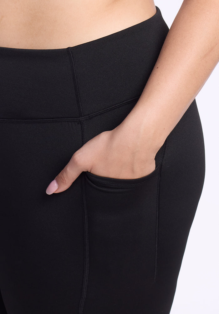 A close-up of a person wearing Woolx Merino Flex® McKenna Capris - Black, with their right hand in a side pocket. These capris feature visible stitching and a high waistband for a perfect blend of comfort and style.