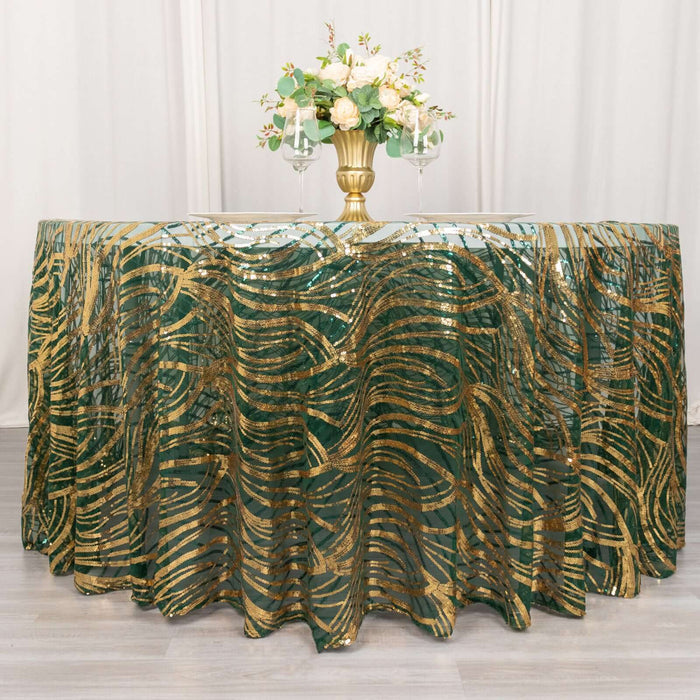 Green and gold wave patterned tablecloth on a table with flowers and glasses.